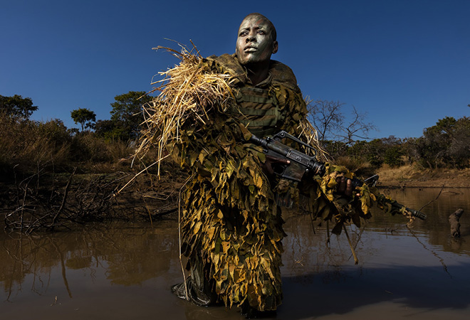 World Press Photo 2019, Environment, Singles, Winner - Akashinga - the Brave Ones © Brent Stirton, Getty Images. Akashinga (The Brave Ones) is a ranger force established as an alternative conservation model. It aims to work with, rather than against local populations, for the long-term benefits of their communities and the environment. Akashinga comprises women from disadvantaged backgrounds, empowering them, offering jobs, and helping local people to benefit directly from the preservation of wildlife. Petronella Chigumbura (30), a member of the all-female anti-poaching unit, participates in stealth and concealment training in the Phundundu Wildlife Park, Zimbabwe.