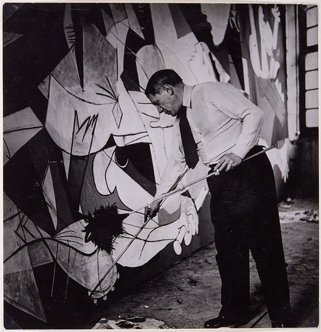 Dora Maar, Picasso de piè trabajando en el Guernica en su taller de los Grands-Augustins, 1937. ©Dora Maar,  ©Succession Picasso by SIAE 2022
