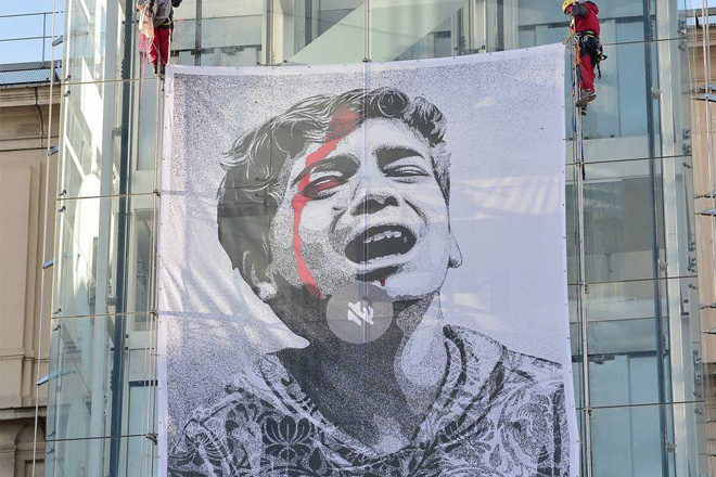 Greenpeace mostra un’opera di Shepard Fairey per il progetto UNMUTE GAZA sulla facciata del Museo Reina Sofia di Madrid