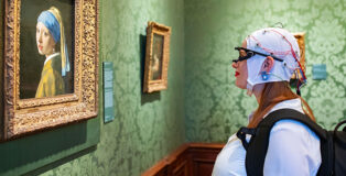 Mauritshuis - Un soggetto dello studio neurologico di fronte al dipinto "La ragazza co l'orecchino di perla" con indosso una cuffia EEG e un eye tracker