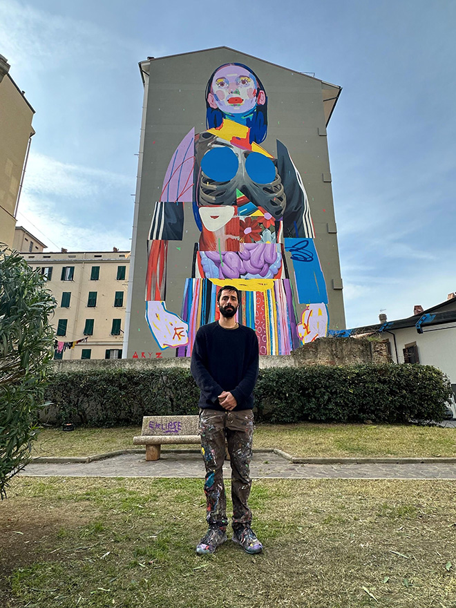 L'artista Aryz di fronte al murale a Livorno nel quartiere Venezia